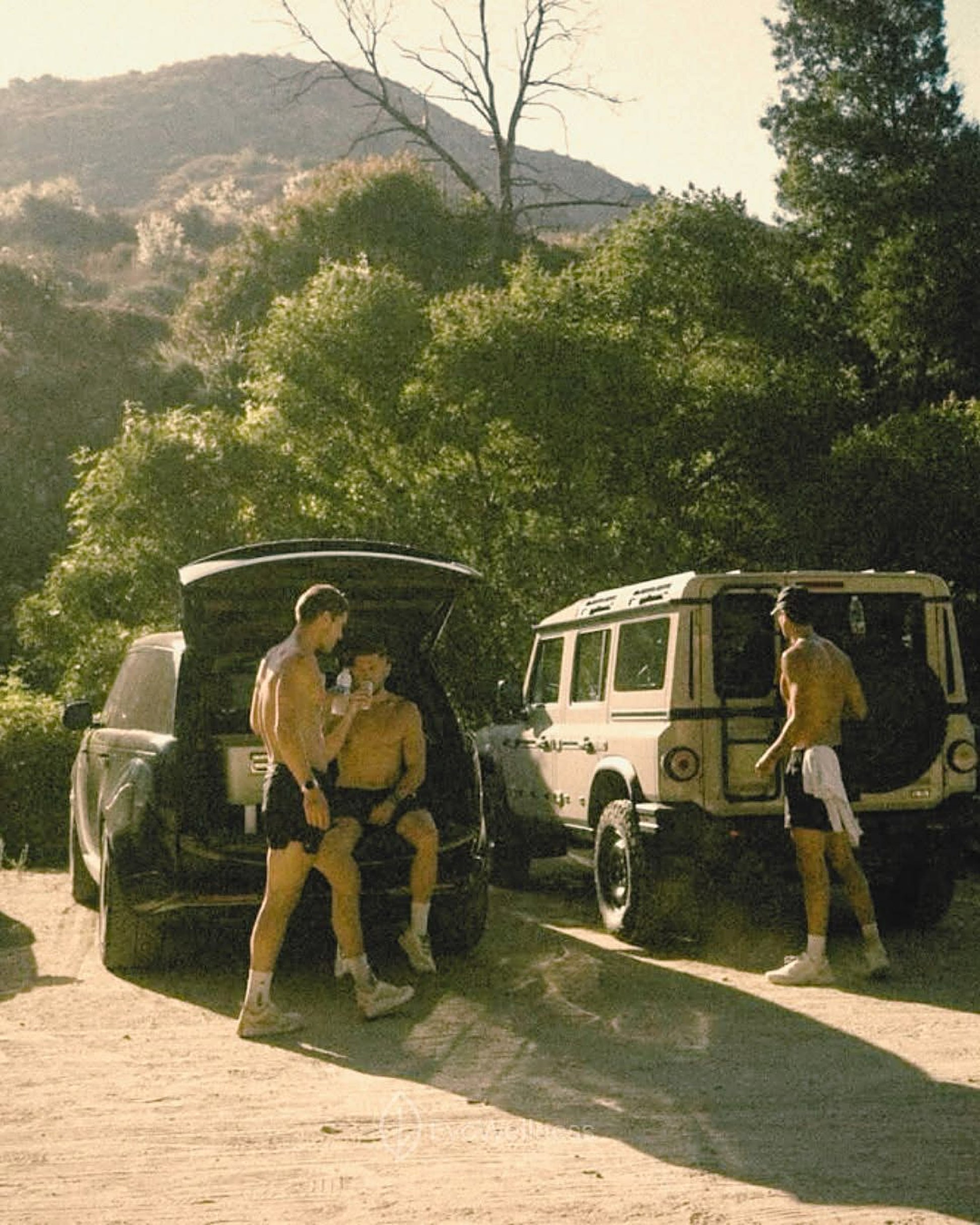 Friends hanging out by two off-road cars on a dirt road
